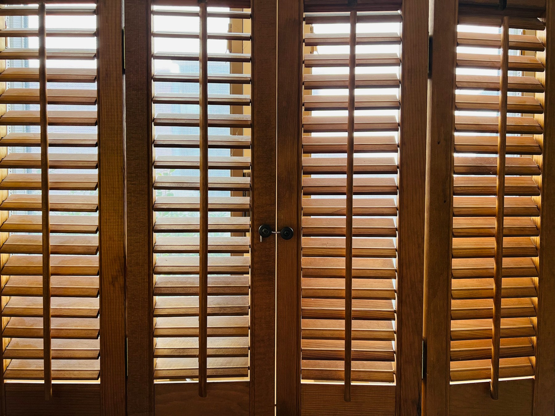 Close view of dark wooden louvered interior shutters across a window.